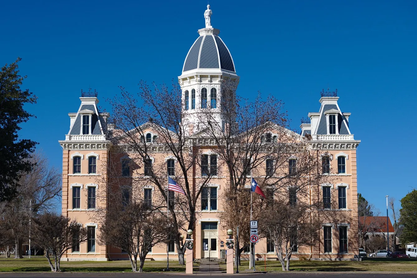 Old brick courthouse with a central dome, under a blue sky.