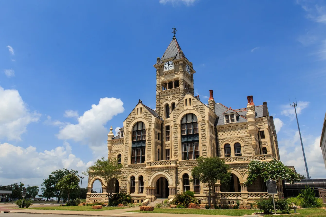 Gothic-style stone courthouse with clock tower against a blue sky.